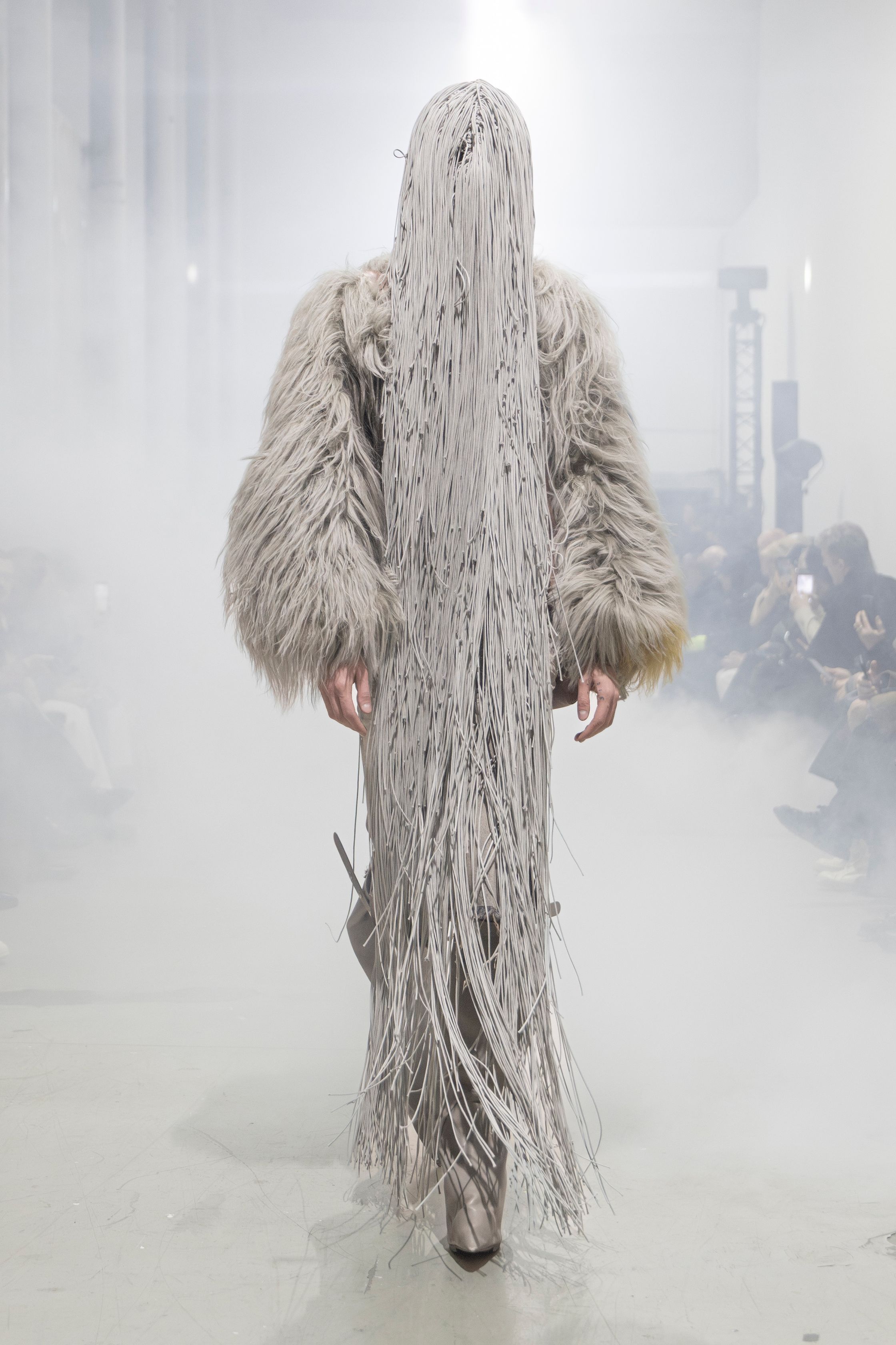 Rick Owens 2026秋冬延续其末世感与宗教式仪式美学。极端肩部结构、皮革与毛感材质在烟雾弥漫的空间中塑造出超越性别的强势身体。系列不再讨论日常，而是关于存在、力量与脆弱的对立统一。行走仿佛一种宣誓，服装成为精神铠甲，彰显Rick Owens一贯的黑暗崇高感-顽石频道趋势研究